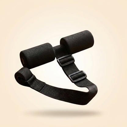 A black adjustable strap with two cylindrical foam padding sections and plastic buckles, shown floating against a warm beige gradient background.